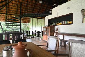 a dining room with tables and chairs in a building at T Stop Farmhouse Coorg in Kurchi