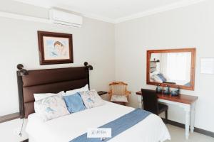 a bedroom with a bed and a desk and a mirror at Mi Vida Guesthouse in Klerksdorp +26 photos