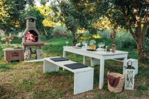 a white table and bench with a fireplace in a yard at House no 1 in Pakoštane +4 photos