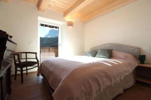 a bedroom with a bed and a chair and a window at Casa Tomà Mountain View Cortina in San Vito di Cadore
