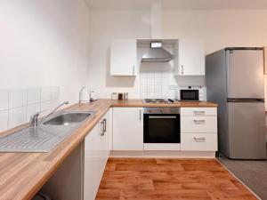 a kitchen with white cabinets and a stainless steel refrigerator at Euston Road - Beach Apartment 9 in Great Yarmouth