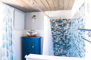 a bathroom with a blue shower curtain and a blue cabinet at Salt & Pine in Mathews, VA in Blackwater +44 photos