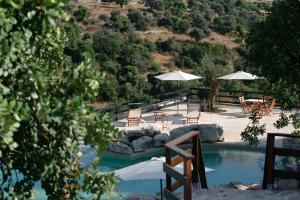 a swimming pool with chairs and umbrellas and a table at Le dimore di Cavalonga in Ragusa
