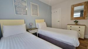 a bedroom with two beds and a mirror and a drawer at 7 The Burrows in Braunton