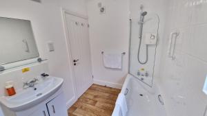 a white bathroom with a sink and a shower at 7 The Burrows in Braunton +14 photos