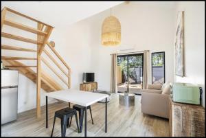 a living room with a white table and a staircase at TI KASA et SPA in Andernos-les-Bains