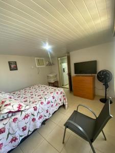 a bedroom with a bed and a chair and a television at Mar e Descanso in Guarapari
