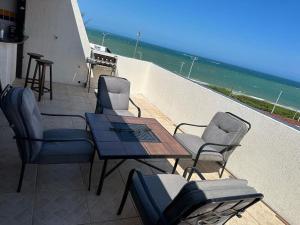 a patio with a table and chairs on the beach at Mar e Descanso in Guarapari +5 photos