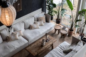 a living room with a white couch and some plants at Noordzee, Hotel & Spa in Cadzand-Bad