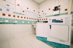a white tiled bathroom with a dishwasher at Eco Stay in Curitiba