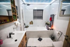 a white bathroom with a tub and a sink at Heated Pool Luxury Retreat - 7 Min from OR Tambo in Benoni +33 photos