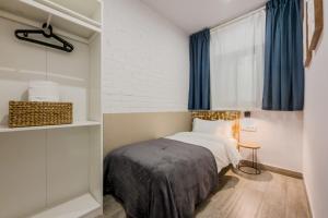 a small bedroom with a bed with blue curtains at Novus Homes Barcelona Santa Eulalia in Hospitalet de Llobregat