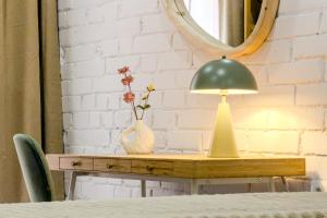 a table with a lamp and a vase with flowers at Novus Homes Barcelona Santa Eulalia in Hospitalet de Llobregat