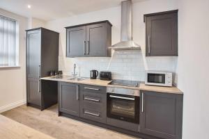 a kitchen with gray cabinets and a microwave at Host & Stay - Promenade Suite in Blackpool
