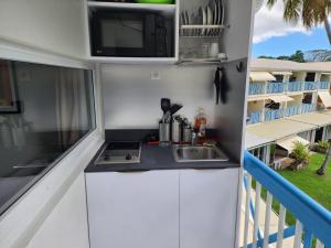 a kitchen with a sink and a microwave on a balcony at Marina View in Les Trois-Îlets