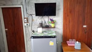 a room with a refrigerator and a tv on a wall at เฮือนอุ้ยดี2 in Ban Khua Nam Chun