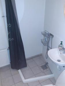 a bathroom with a black shower curtain and a sink at Stor lejlighed ved togstation in Viborg +11 photos