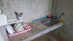 a kitchen counter with a sink and plates and pans at เฮือนอุ้ยดี2 in Ban Khua Nam Chun