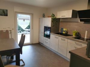 a kitchen with white cabinets and a table and a window at Ferienwohnung DORFWIESE in NuÃŸbaum