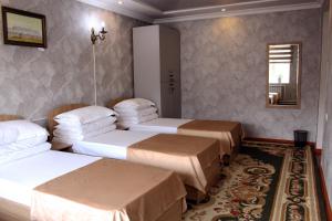a hotel room with three beds and a mirror at Bozui Hostel Osh in Osh