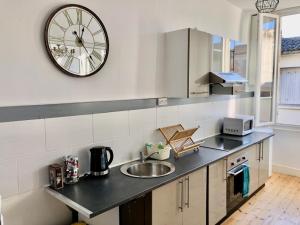 a kitchen with a sink and a clock on the wall at Centre ville 38 Maréchaux in Saint-Jean-dʼAngély