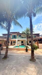 a house with two palm trees and a swimming pool at Recanto da Mari in Paraty