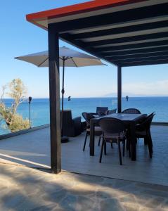 a patio with tables and chairs and a view of the ocean at La Mer Villa - Entire Cottage in Plomari