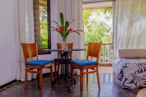 a table with three chairs and a vase with flowers on it at Kombo Oasis in Serekunda