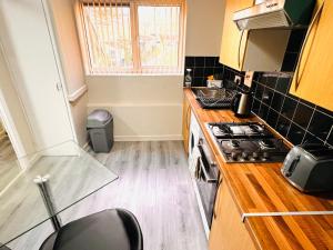 a small kitchen with a stove and a window at Modern 1-Bed Flat Near Northampton General Hopital Town Centre & M1 in Spinney Hill +24 photos