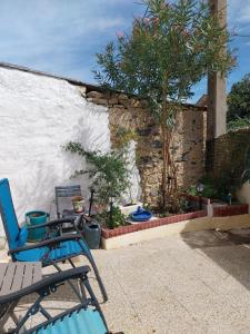 a patio with two chairs and a tree next to a wall at Les aires in Tourbes