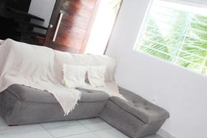 a couch with a blanket sitting next to a window at Duplex Apartamento em Casa Caiada in Olinda