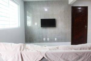 a bedroom with a bed and a tv on a wall at Duplex Apartamento em Casa Caiada in Olinda