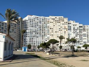 a large white building with palm trees in front of it at Sweet Dreams Apartment, estilo y confort en 1ª línea, Renovado, Práctico y Anfitrión 5 Estrellas" in Empuriabrava