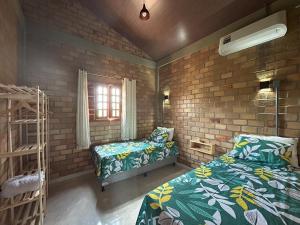 a bedroom with two beds and a brick wall at Bella Casa Ipê 1º andar APA Barra de Mamanguape in Rio Tinto