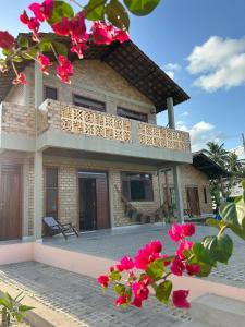 a house with a balcony and pink flowers at Bella Casa Ipê 1º andar APA Barra de Mamanguape in Rio Tinto