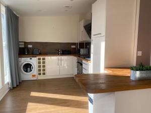 a kitchen with white cabinets and a washer and dryer at Newcastle City Penthouse in Newcastle upon Tyne +8 photos