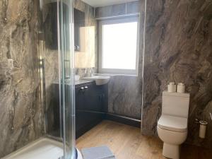 a bathroom with a shower and a toilet and a window at Newcastle City Penthouse in Newcastle upon Tyne