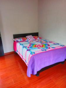 a bed with a colorful comforter in a room at Finca La Milagrosa in Cómbita