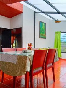 a dining room with a table and red chairs at Finca La Milagrosa in Cómbita