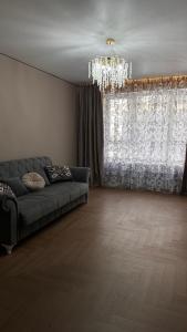 a living room with a couch and a chandelier at Turar apartments in Almaty
