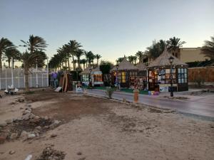 a street with some stores and palm trees and a road at Porto Sharm Family Chalet with Pool View in Sharm El Sheikh