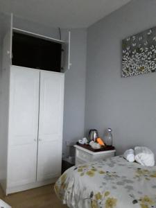 a bedroom with a white cabinet and a bed at HomefromHome in Rosslare
