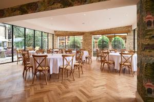 a dining room with tables and chairs and large windows at The Old Bell Hotel in Malmesbury