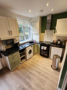 a kitchen with green and white cabinets and a stove at Bank End Cottage in Almondbury