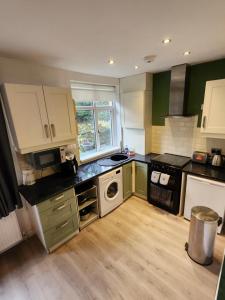 a kitchen with green and white cabinets and a stove at Bank End Cottage in Almondbury +12 photos