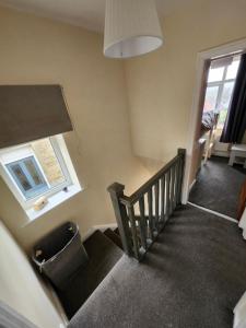 a room with a staircase with a chair and a window at Bank End Cottage in Almondbury