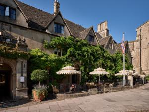 a building with tables and umbrellas on a street at The Old Bell Hotel in Malmesbury