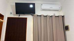 a flat screen tv on the wall above a curtain at Pousada Bela Rainha in Aparecida