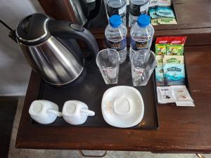 a table with a tea kettle and cups and water bottles at Kandy City Inn in Kandy