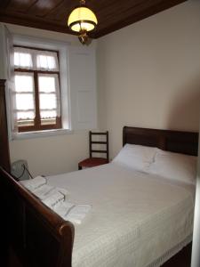 Un dormitorio con una cama con sábanas blancas y una ventana. en Casa de RioBom, en Soajo